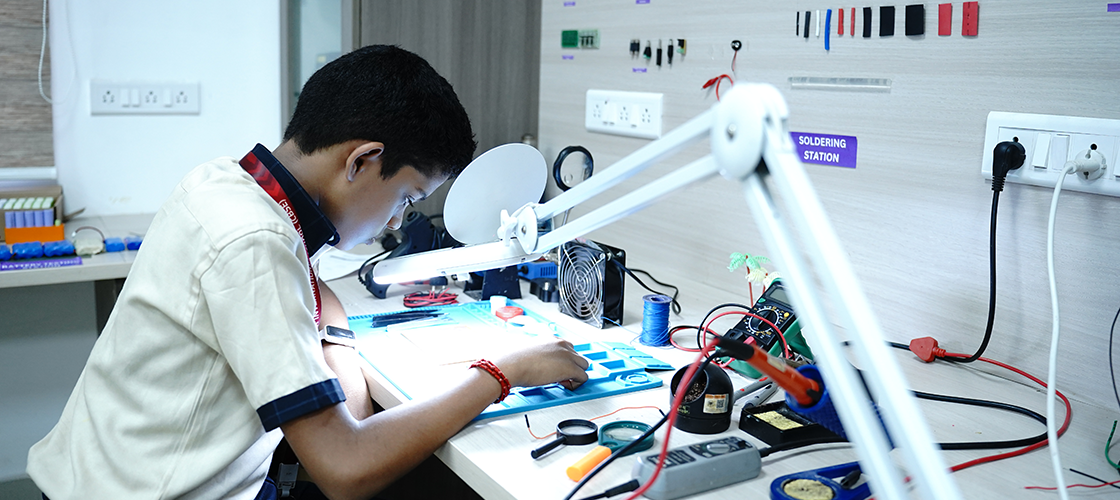 Precision in progress! A focused young innovator carefully assembles a circuit, learning the art of soldering and the science of electronics.